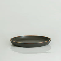 A 10'' black stoneware dinner plate with a swirl pattern on a white background.